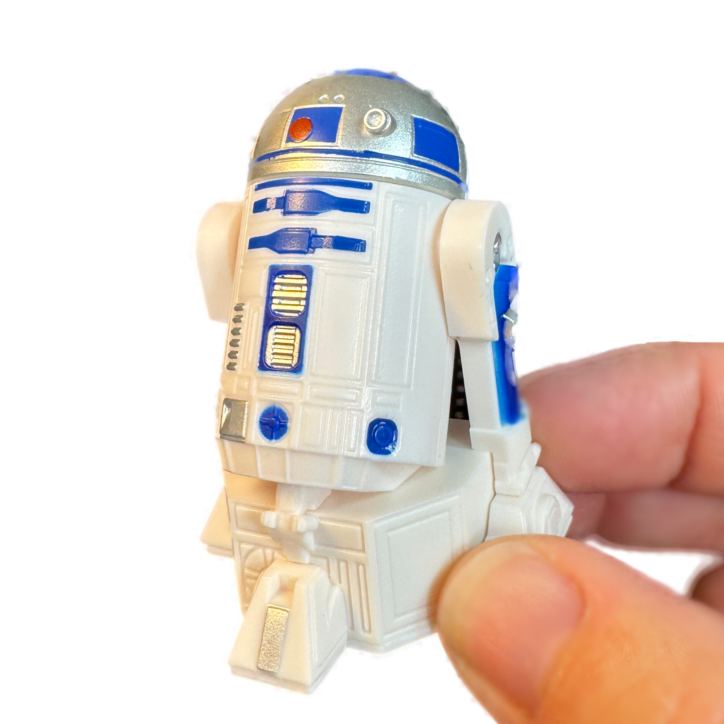 A hand holds an R2-D2 Star Wars droid toy gachapon.