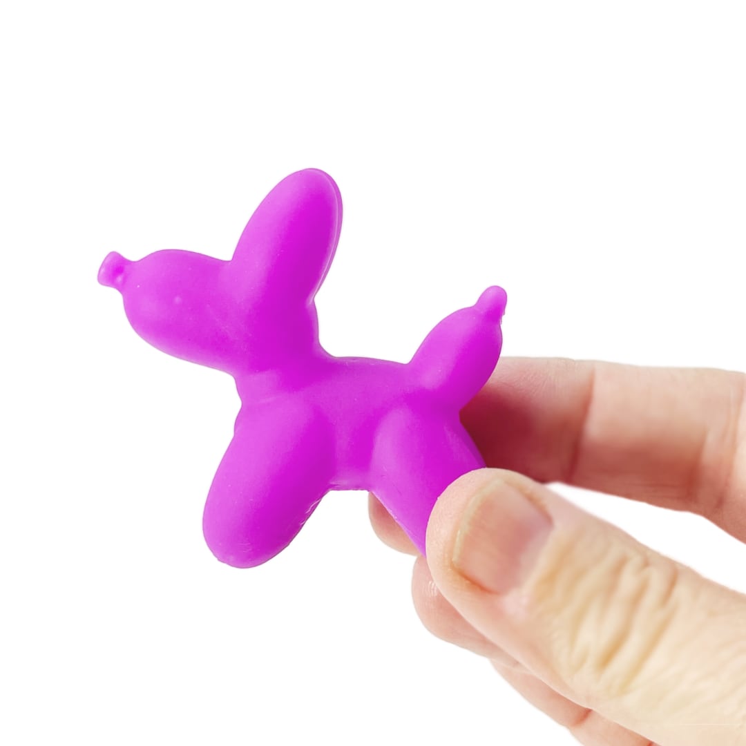 A hand holds a small purple balloon toy dog.