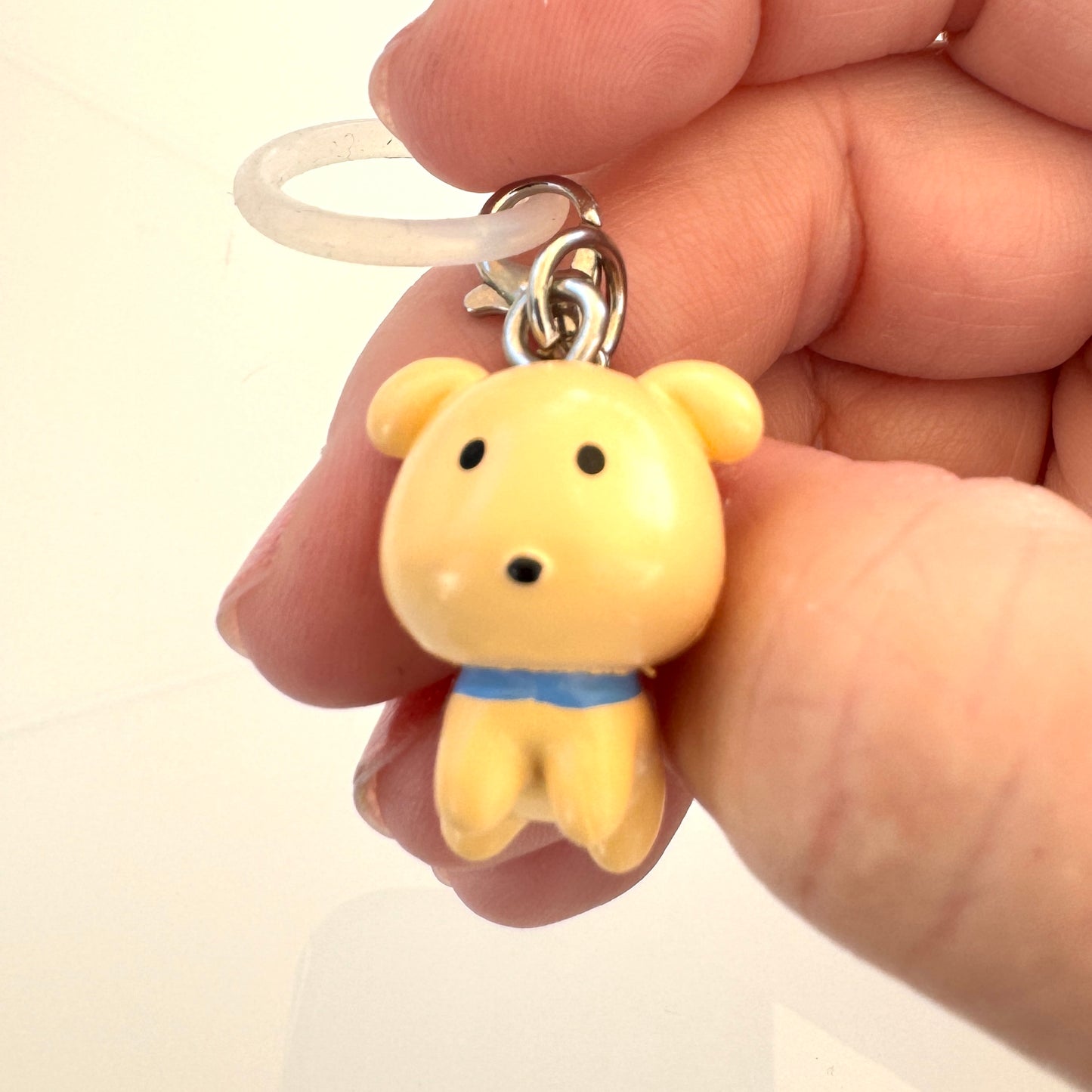 Yellow dog-shaped keychain held in a hand against a white background