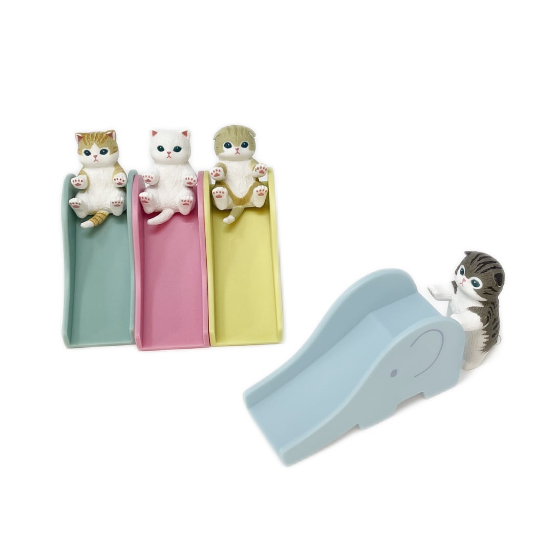 Four small toy cat figurines are pictured next to four toy slides in the shape of an elephant. Each figurine has a unique design.