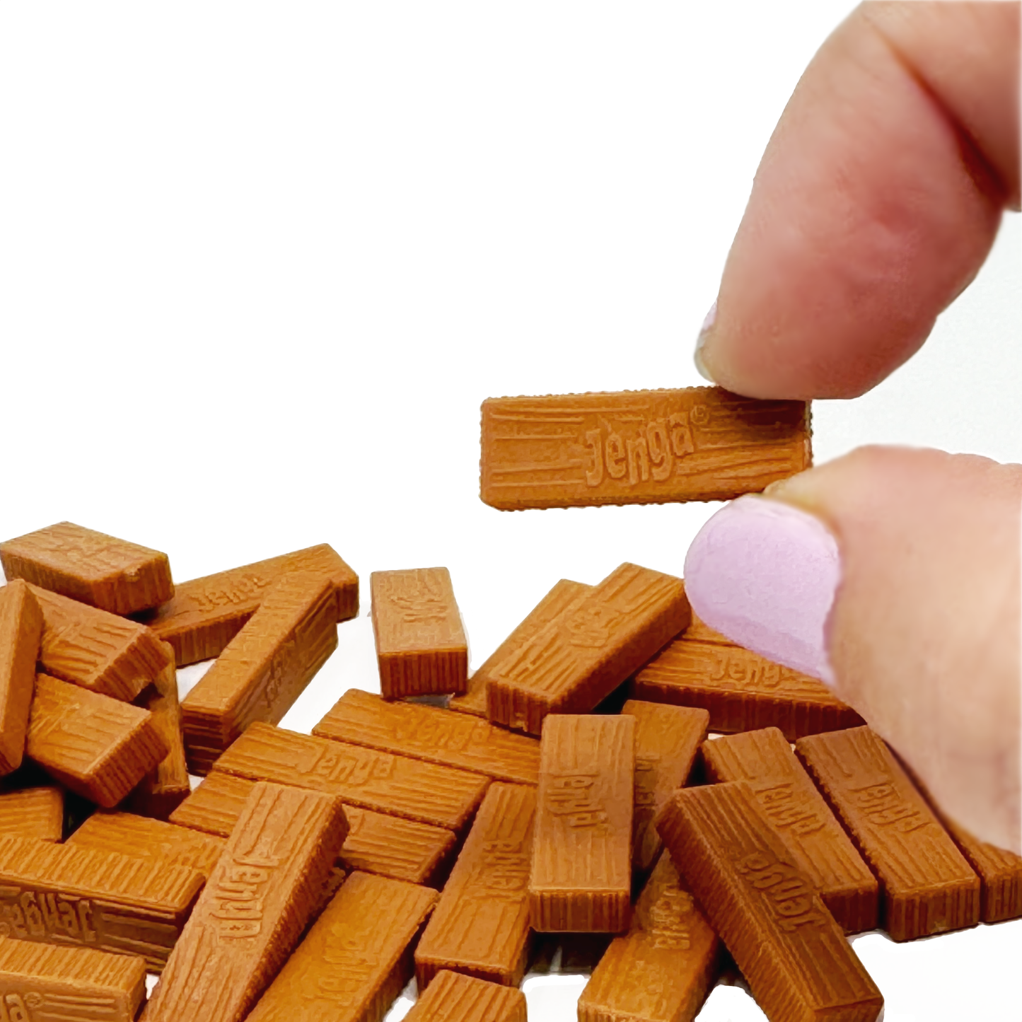 A finger holds a tiny block from a pile on the table of The World's Smallest Jenga.