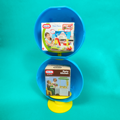 A surprise toy ball turned into a stand holding the packaging for Tikes Place and Party Kitchen from two Miniverse Mini Little Tikes Series 3 on a teal background