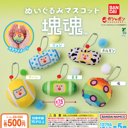 Japanese Bandai Namco Gashapon toy capsule packaging showing five colorful plush squeeze toys with cartoon faces, including a tennis ball, green capsule, cow-print, blue polka dot, and orange patterned designs on a pale green background.