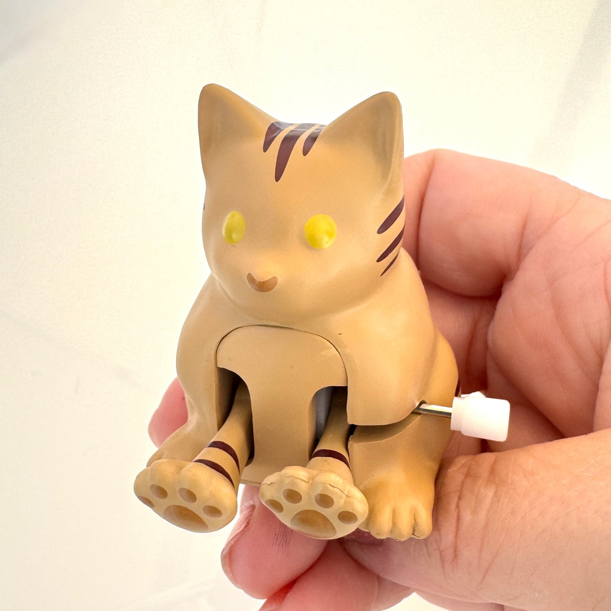 Cat-shaped toy held in a hand against a plain background