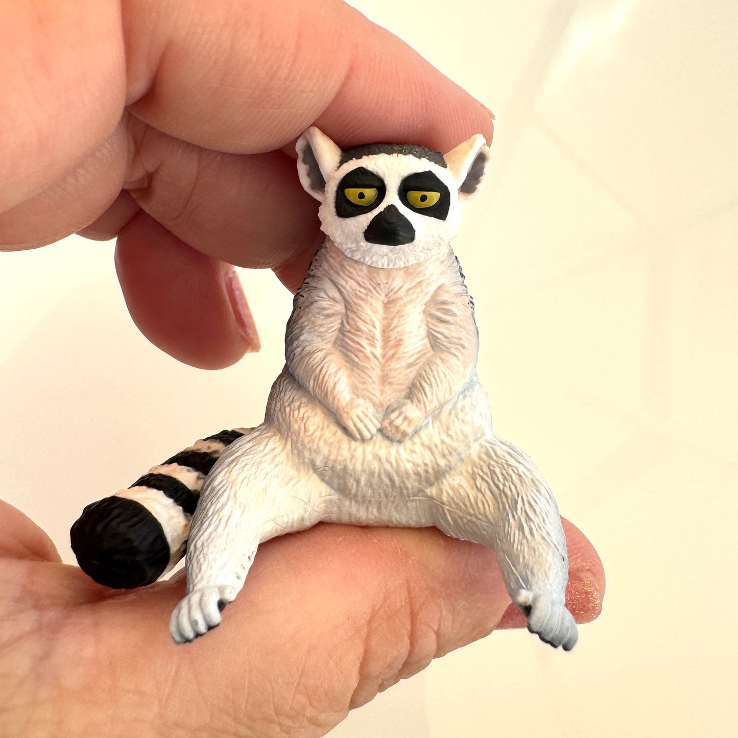 Toy lemur held in a hand against a plain background