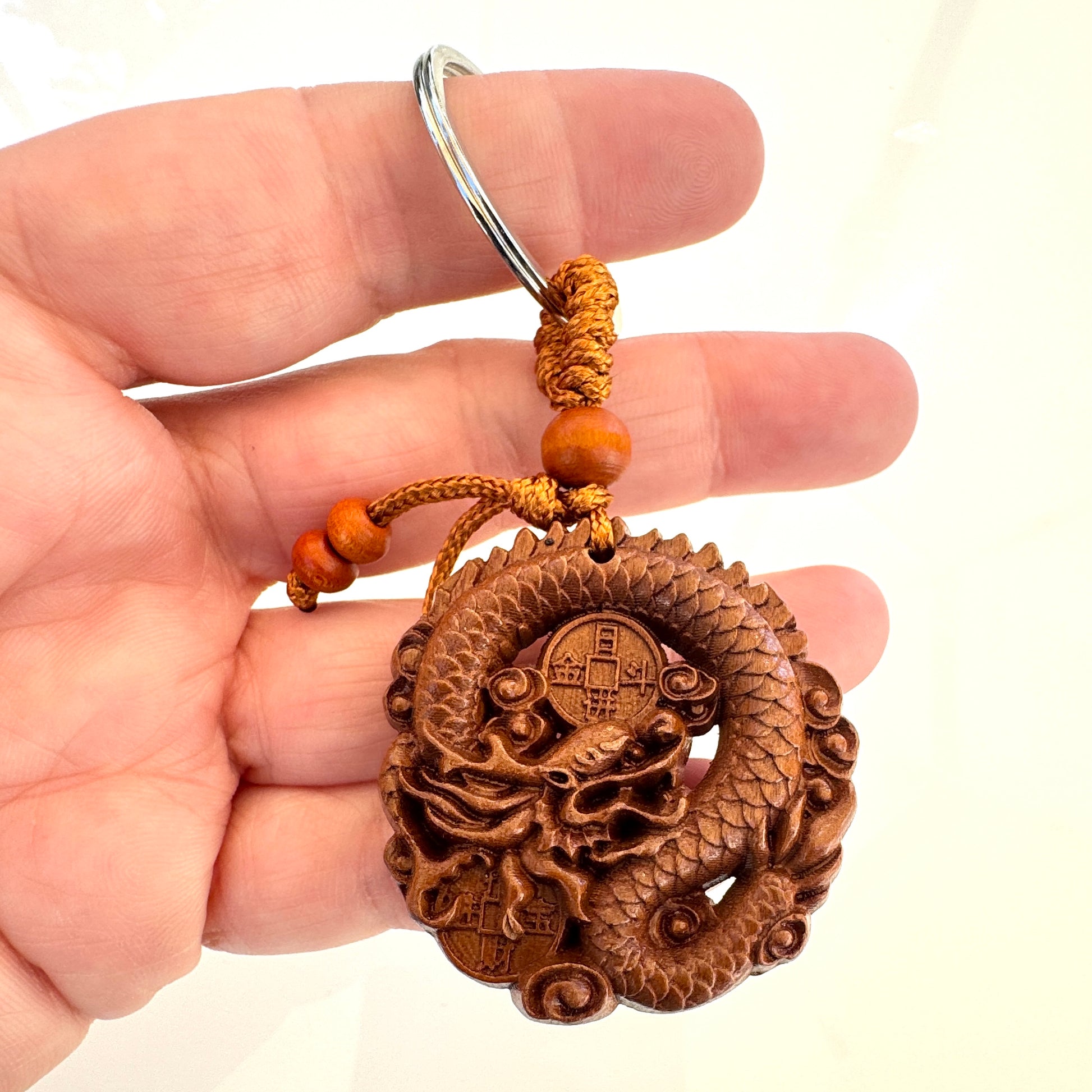 Wooden dragon keychain held in a hand against a white background