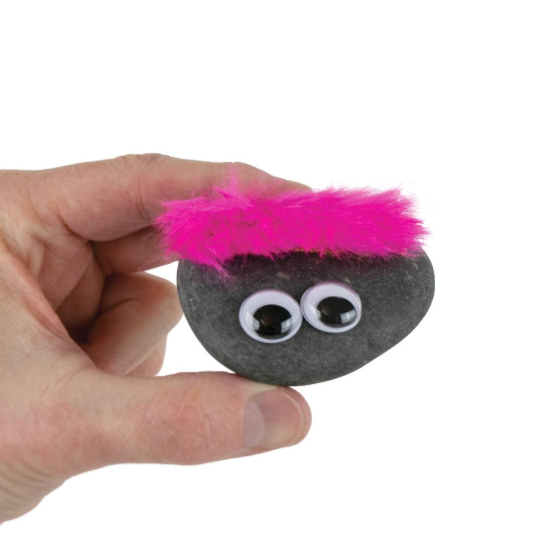 A hand is holding an Original Classic Pet Rock with goggly eyes and pink hair.