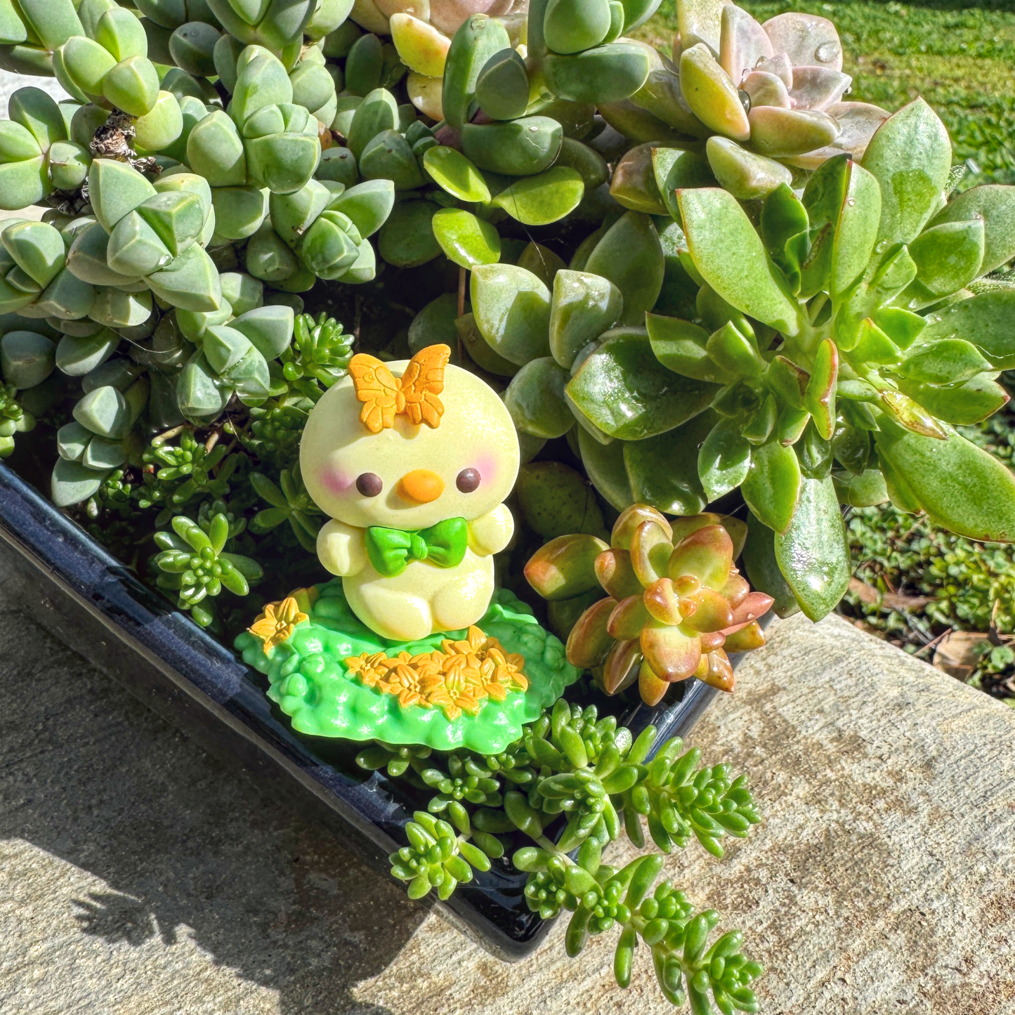 A tiny toy duck rest in the garden.